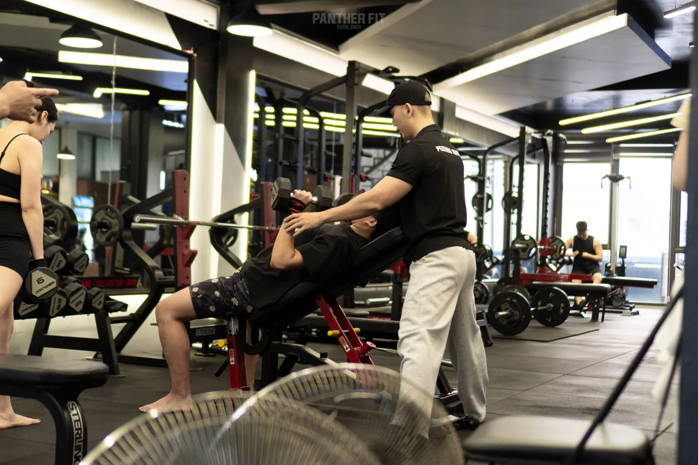 Huấn luyện viên Hà Quyết đang hỗ trợ hội viên tập tạ tay tại Panther Fit